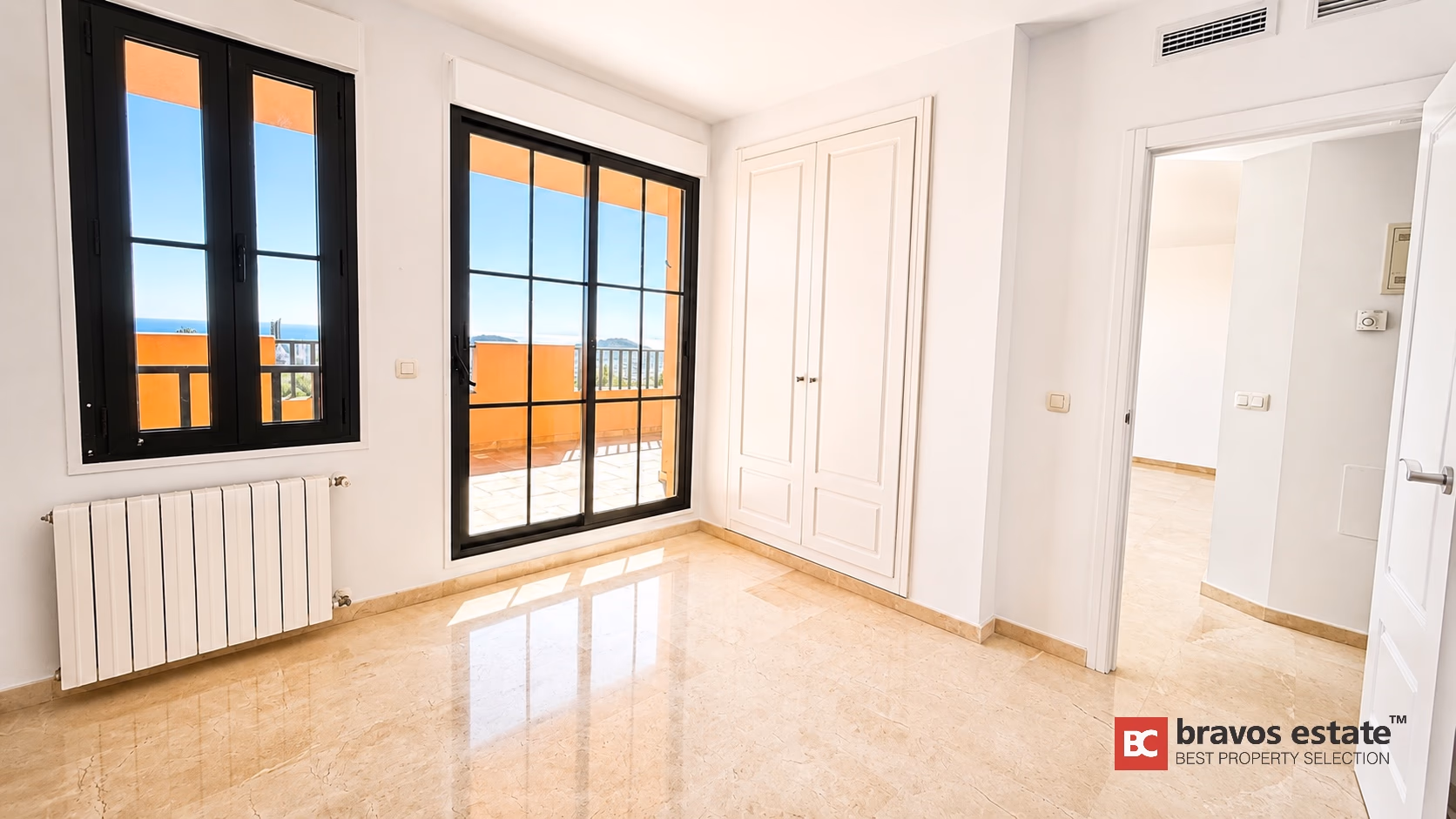 Chambre avec armoires intégrées et portes coulissantes ouvrant sur terrasse avec vue mer