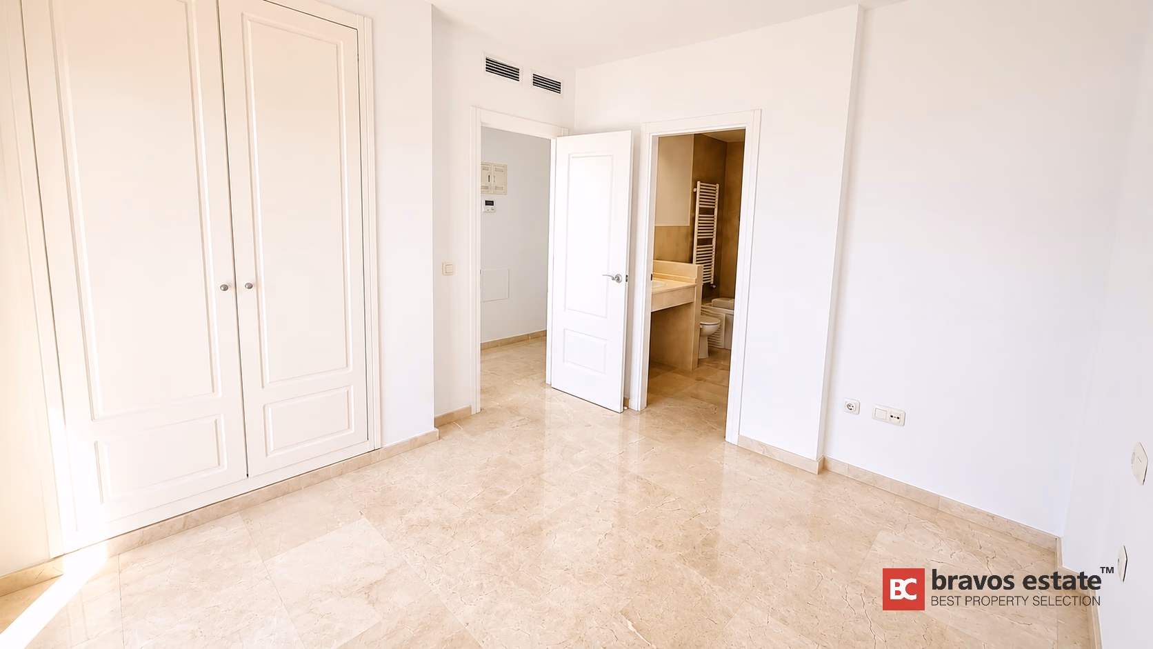 Chambre avec armoires encastrées blanches et accès salle de bain attenante