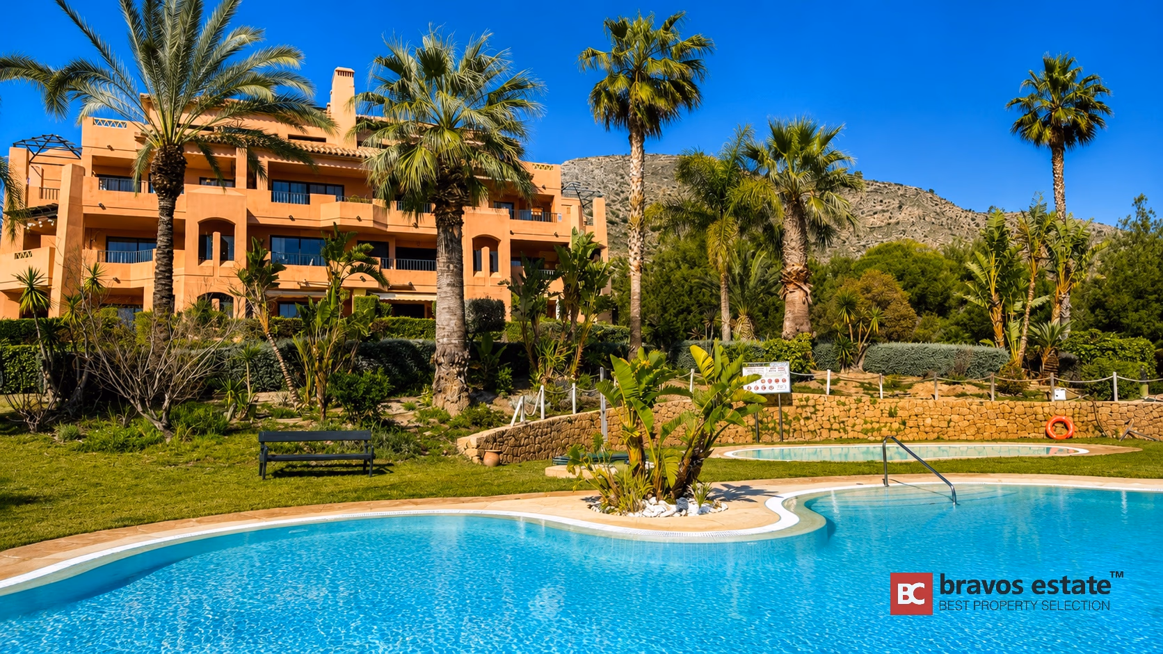 Résidence Sierra Cortina à Finestrat avec façade terracotta, deux piscines, palmiers et vue sur la montagne