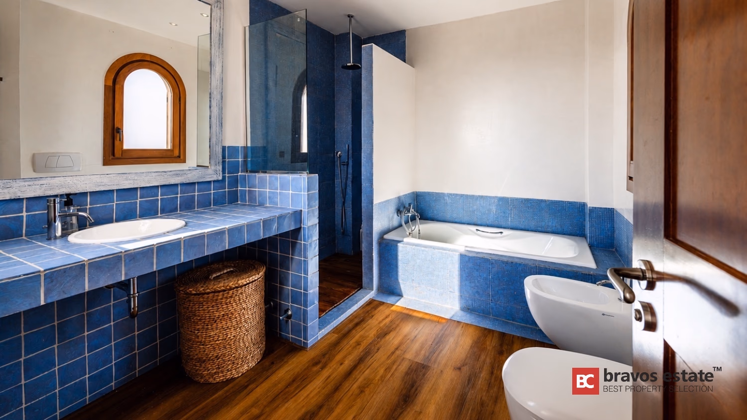 Badezimmer der Villa Ibiza mit blauen Fliesen, Badewanne, ebenerdiger Dusche und Bogenfenster