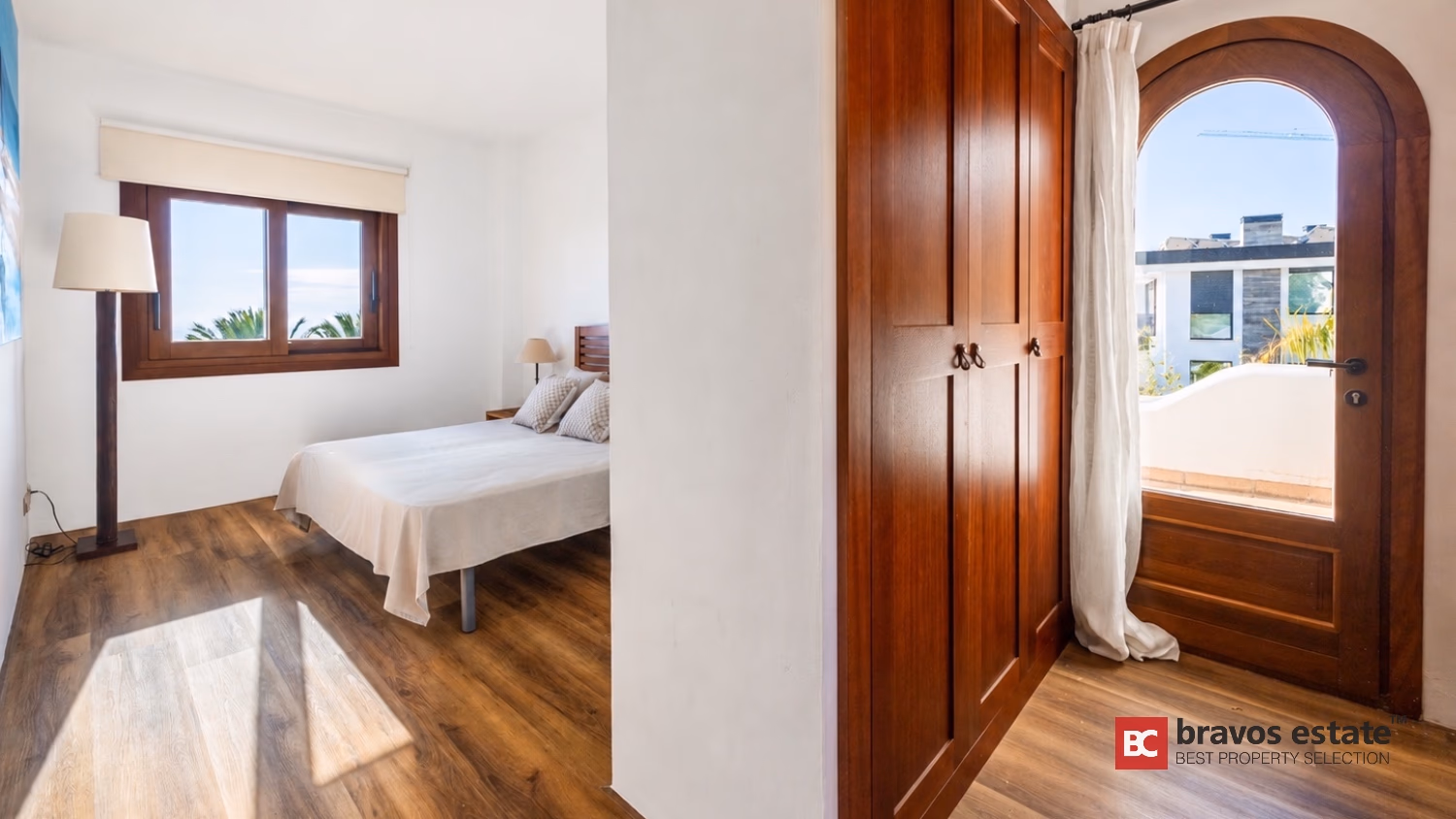 Schlafzimmer mit Einbauschränken aus Holz und Bogenfenster in der Villa Ibiza