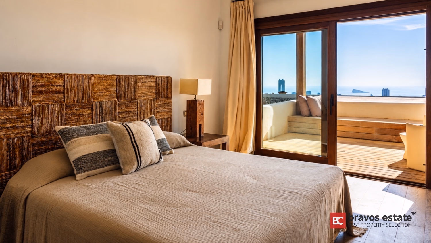 Schlafzimmer mit Korbgeflecht-Kopfteil und Schiebetüren mit Meerblick in Villa Ibiza