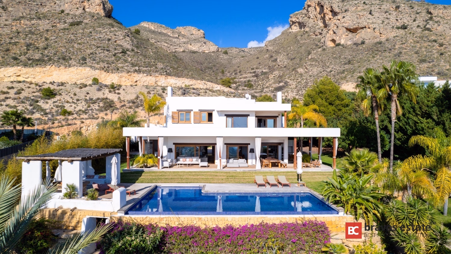 Villa Ibiza Frontansicht mit privatem Pool, mediterranem Garten und Felsengebirge in Sierra Cortina Resort