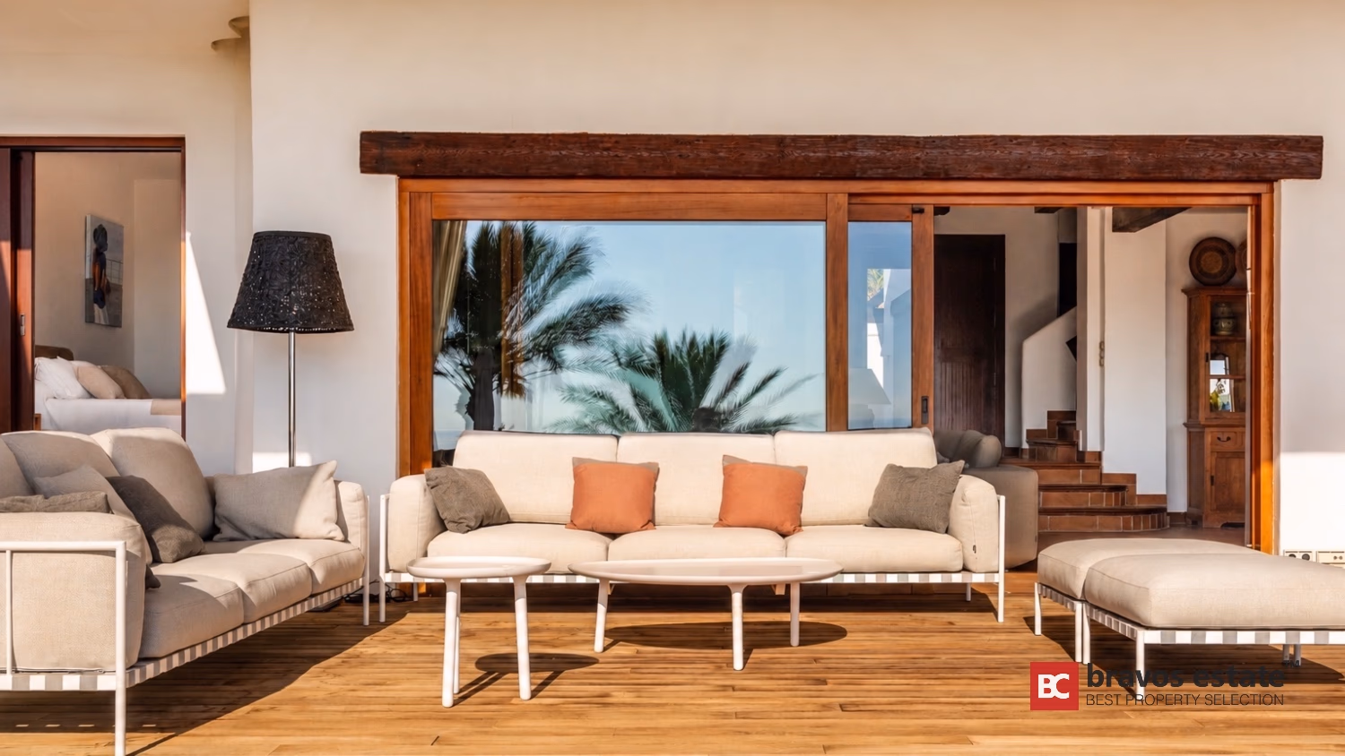 Wohnzimmer der Villa Ibiza mit cremefarbenen Sofas, freiliegendem Holzbalken und Schiebetüren zur Terrasse