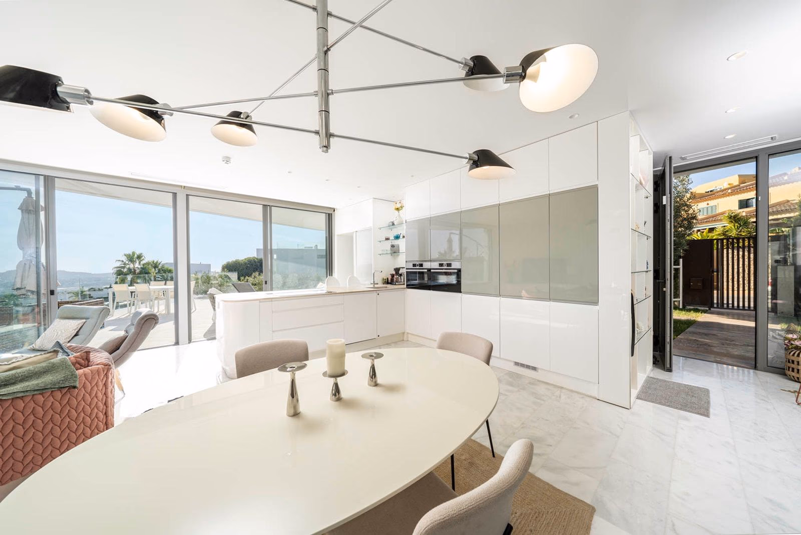 Open keuken-eetkamer met sculpturale hanglampen en terrasdoorgang