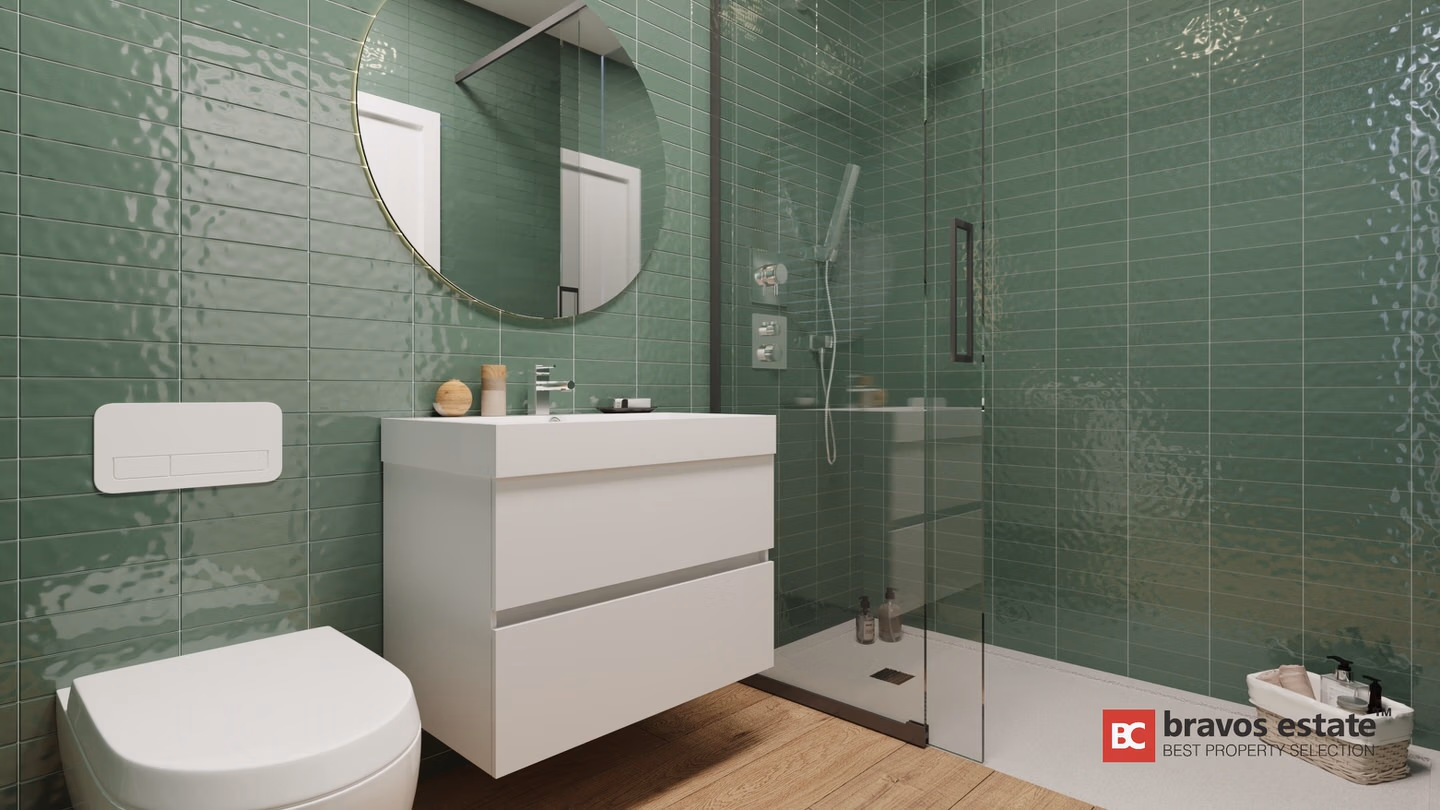 Render CGI del cuarto de baño de un apartamento de Bonalba Green con azulejos verdes brillantes, inodoro suspendido, mueble de baño blanco flotante, espejo redondo con marco dorado y ducha de obra con mampara de cristal.