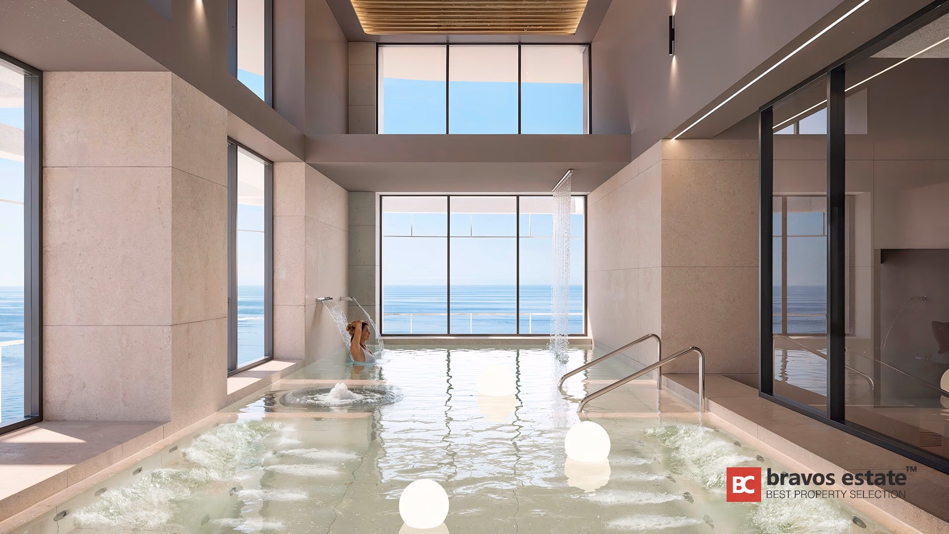 Indoor hydrotherapy pool with waterfall jets, travertine walls, and panoramic sea views at TM Tower Benidorm