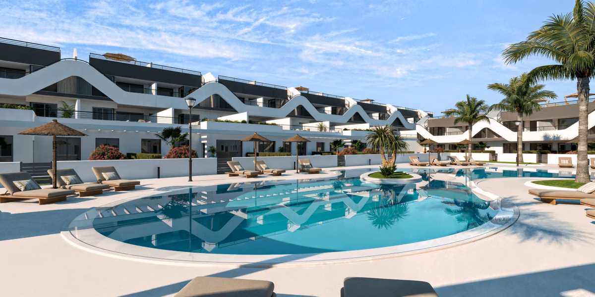 Sawtooth-roofed white blocks of Alfaz Essence above the pool