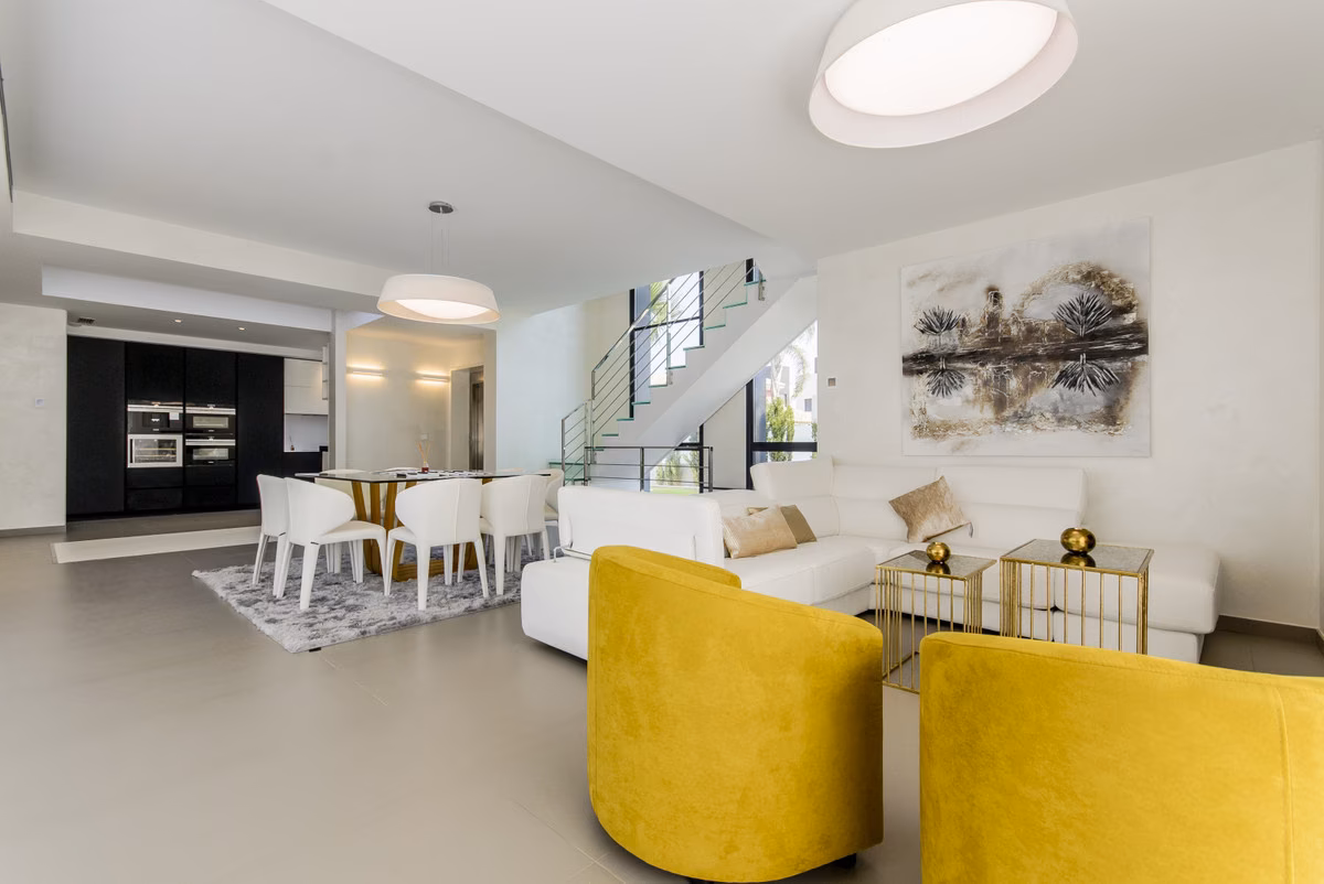 Open-plan living and dining area with glass staircase at Amay Deluxe