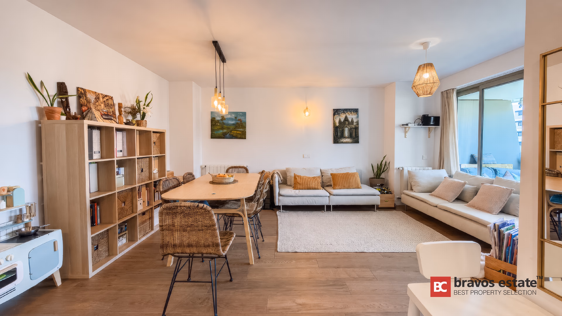 Living room with a cream sofa, shelving unit and sliding doors to the terrace