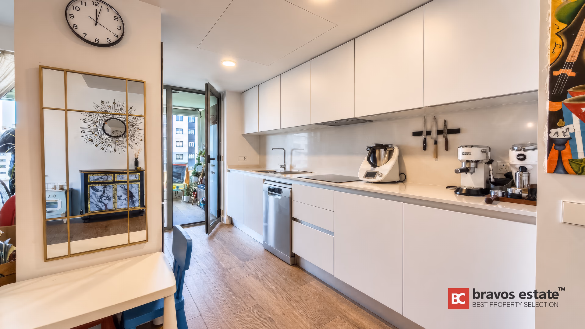 White kitchen with induction hob, dishwasher and a window to the terrace
