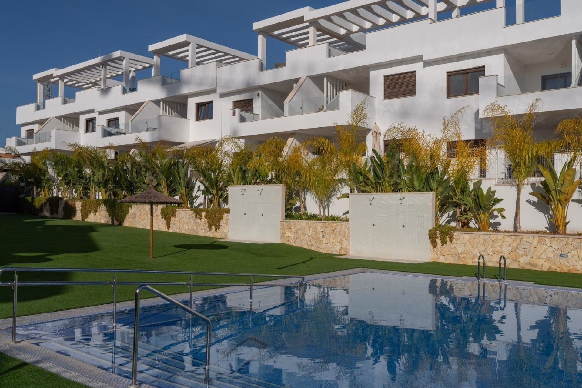 Communal pool and gardens in front of the white apartment blocks in Balcón de Finestrat