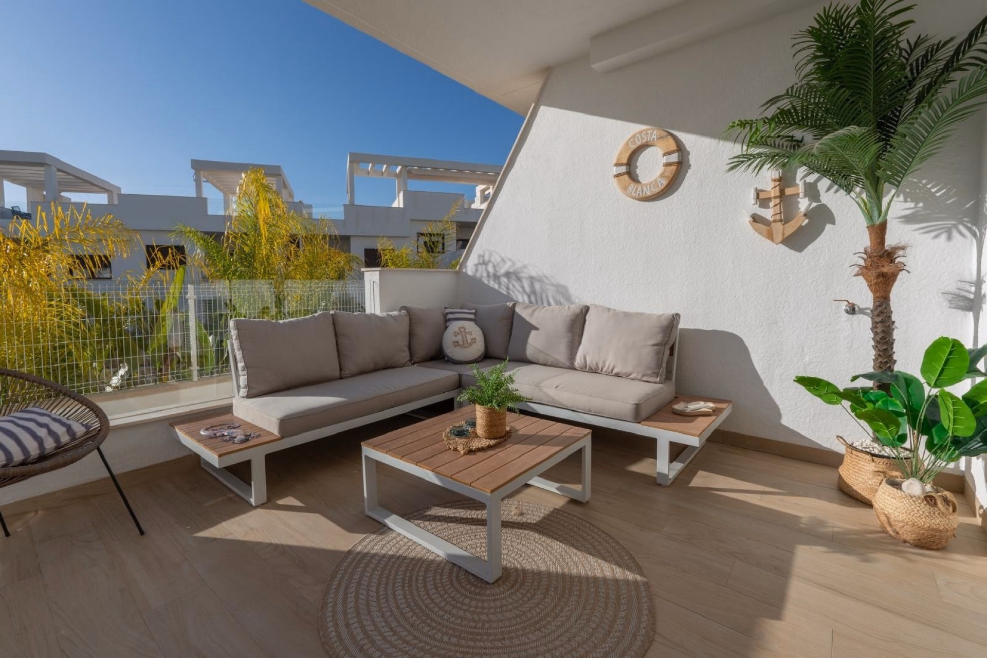 Terrace seating area with a white wall, palm and parasol