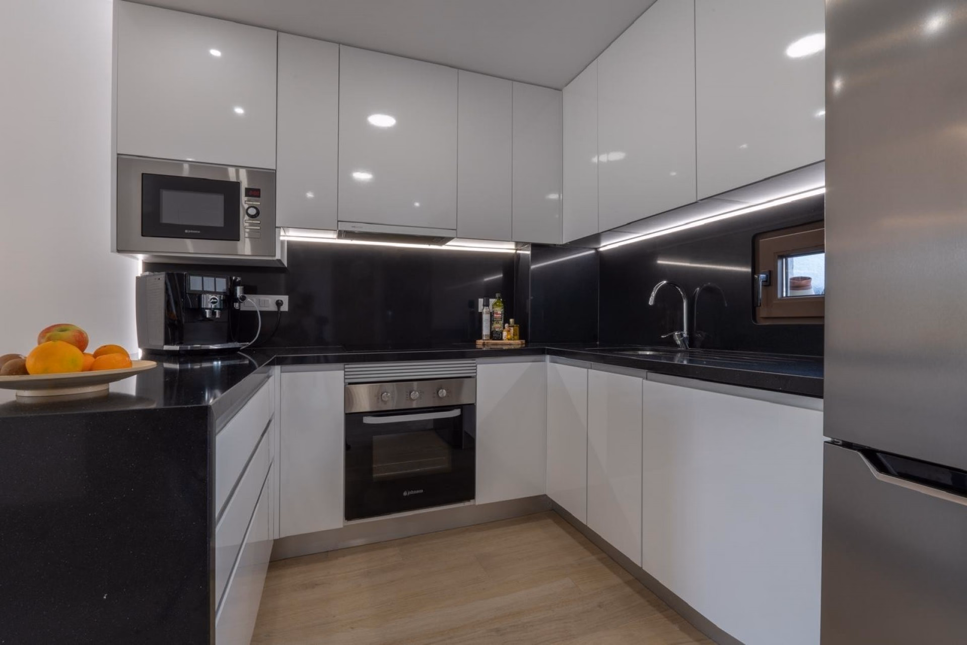 White gloss kitchen with black worktops, built-in oven and microwave