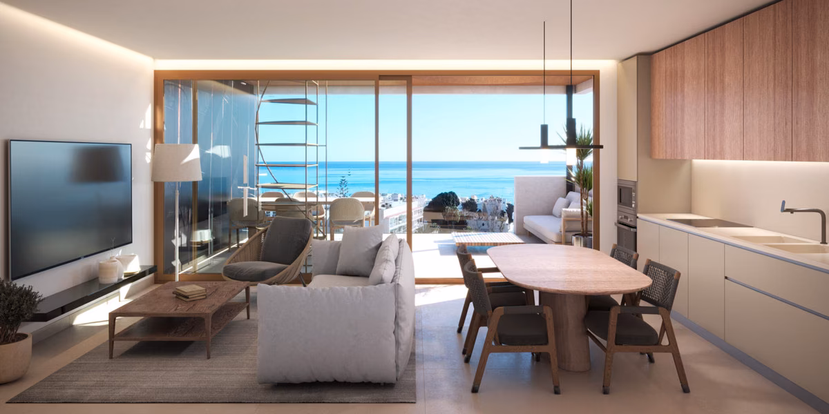 Open-plan living and dining area with fitted kitchen and sea view through glass doors