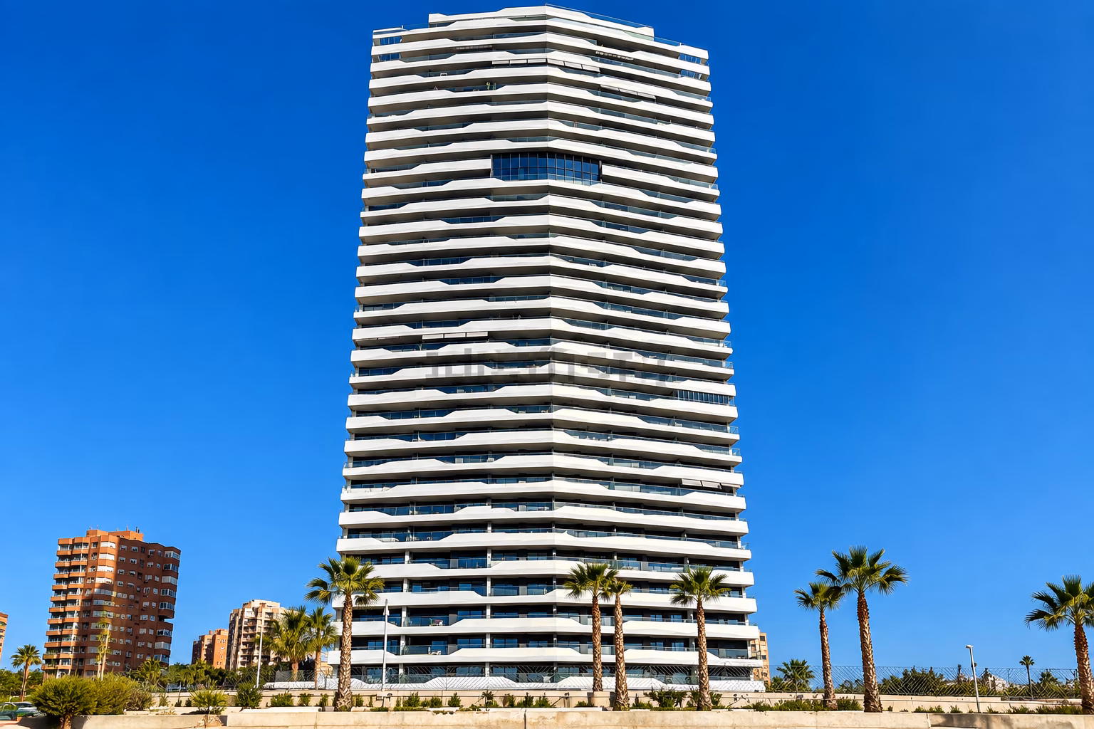 Torre residencial blanca con balcones ondulados