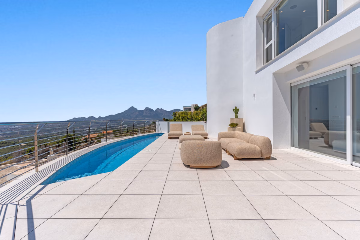 Larga piscina privada junto a la terraza y la fachada blanca curva
