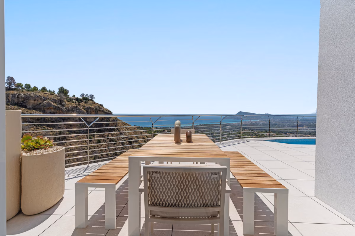 Mesa de comedor exterior junto a la piscina con vistas a la bahía