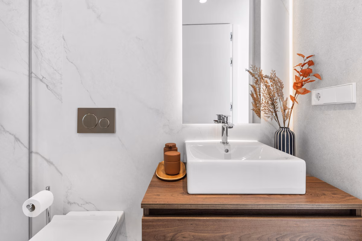 Baño de mármol con lavabo sobre encimera en un mueble de nogal