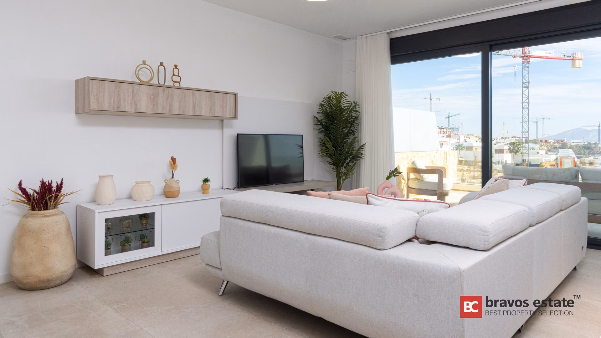 Séjour avec canapé blanc et baies vitrées dans un appartement témoin de Camporrosso