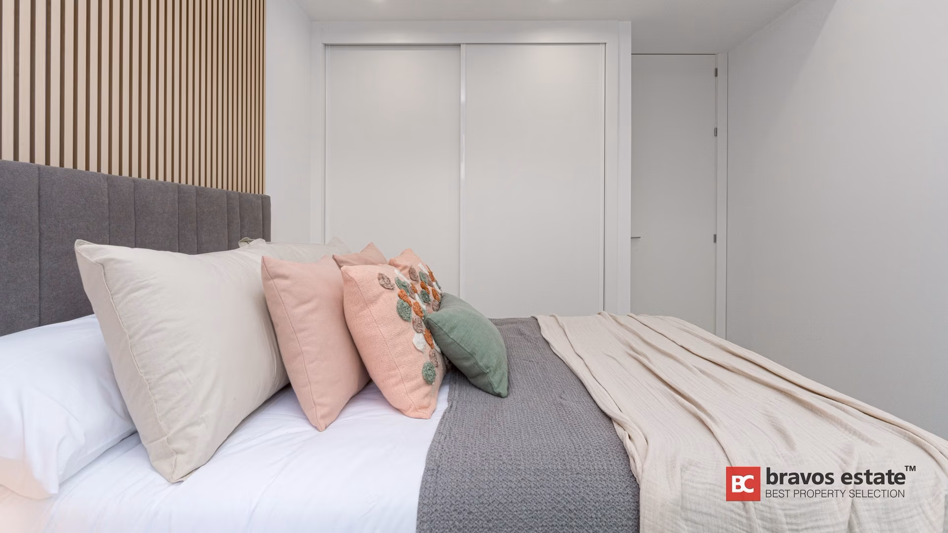 Chambre avec coussins roses et placard intégré dans un appartement témoin de Camporrosso