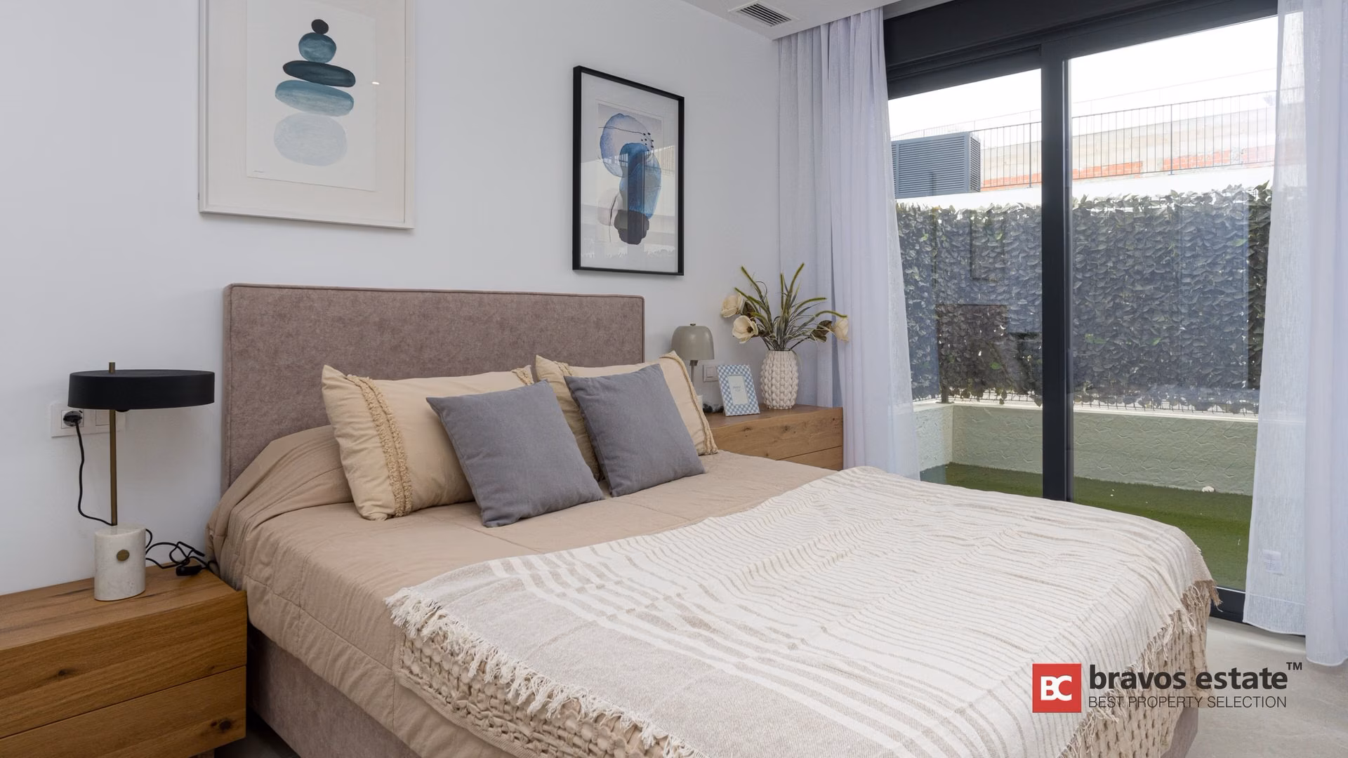 Chambre avec tableaux et lampes de chevet dans un appartement témoin de Camporrosso