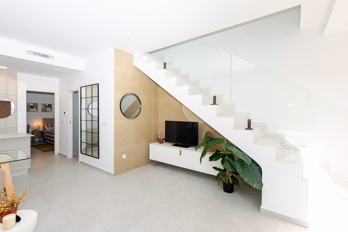Staircase with glass balustrade above a TV unit and wood-panelled wall