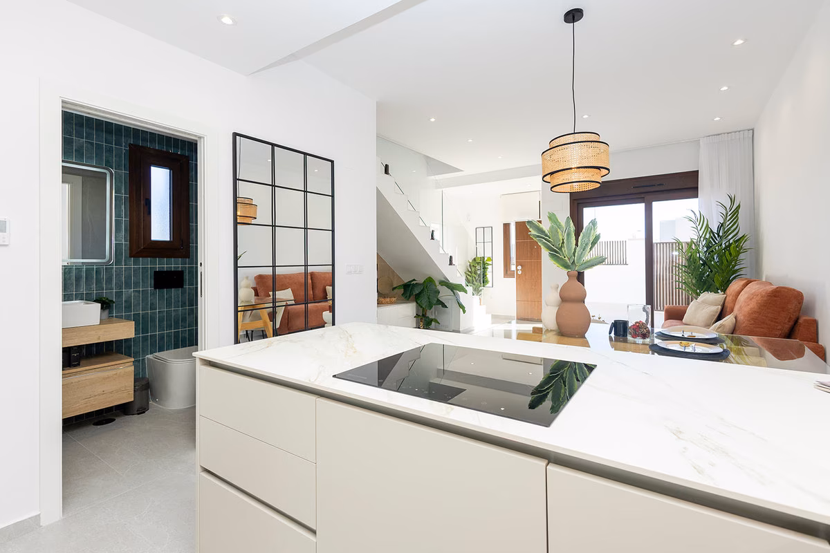 Kitchen island with hob, and a bathroom with green tiles beyond
