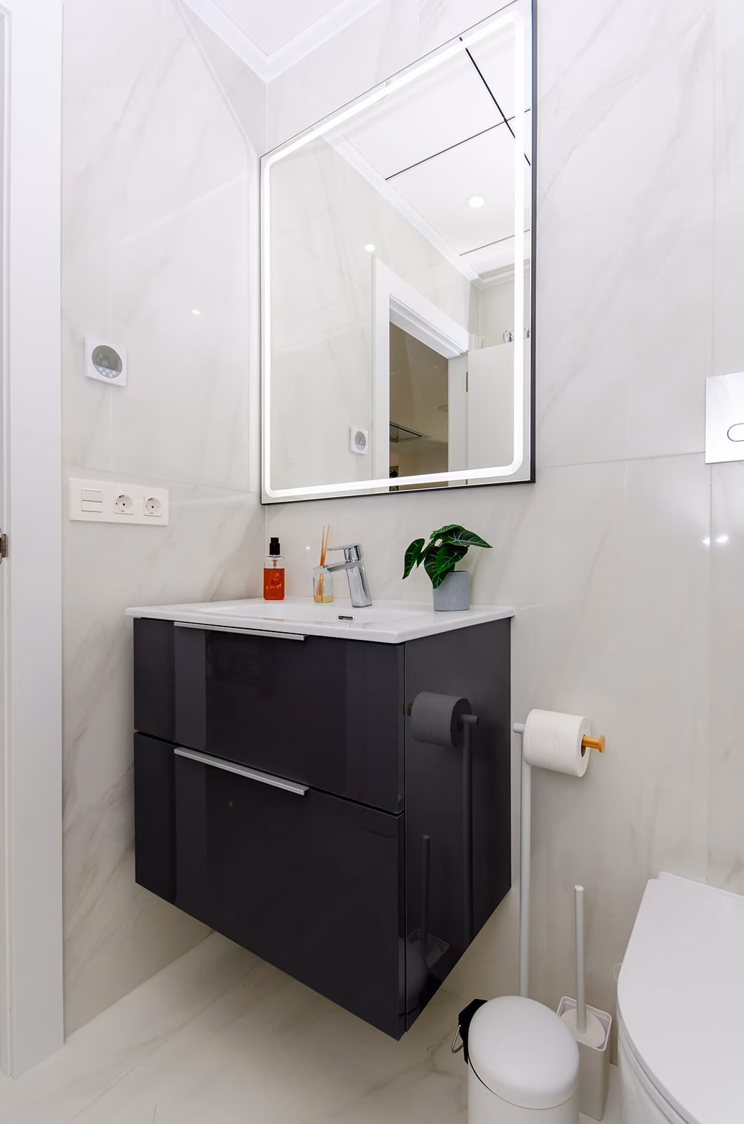 Bathroom with dark grey vanity and backlit mirror