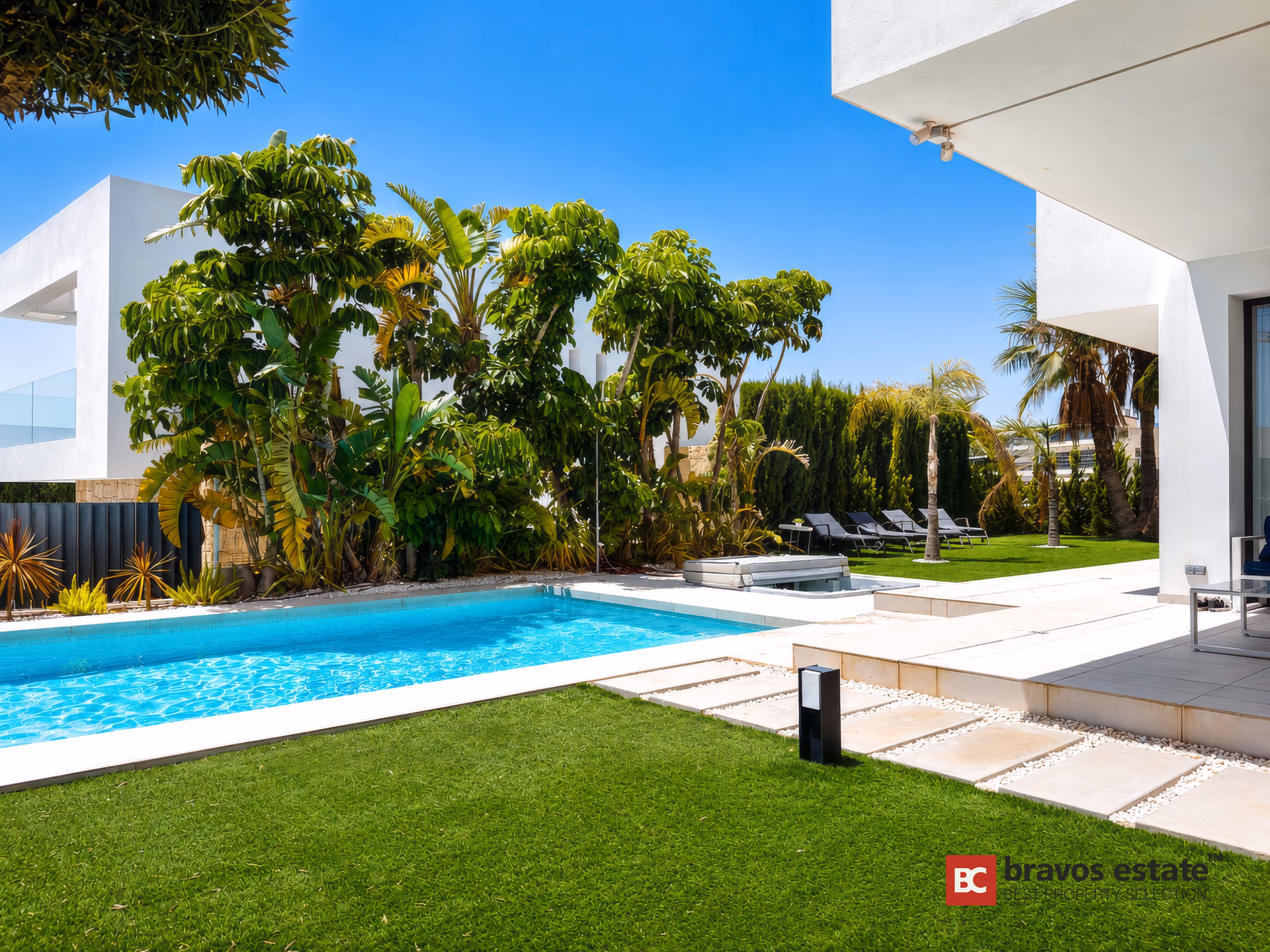 Jardin en pelouse avec piscine et palmiers