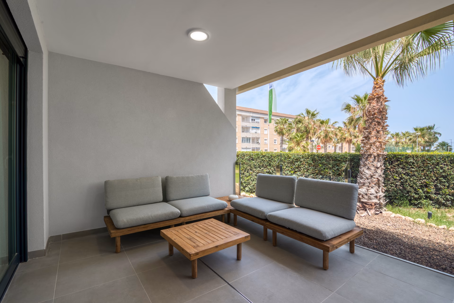 Terrasse lounge sous l’immeuble avec vue palmiers