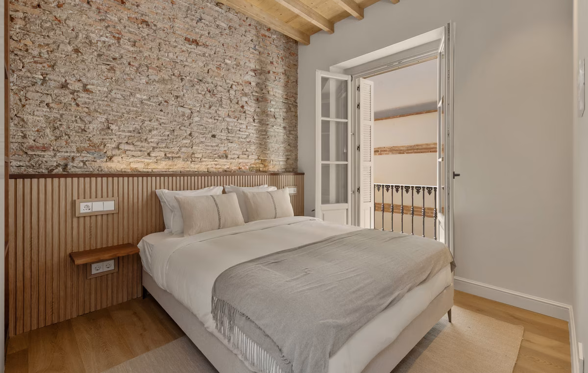 Schlafzimmer mit Holzpaneel am Kopfende und Sprossenfenster