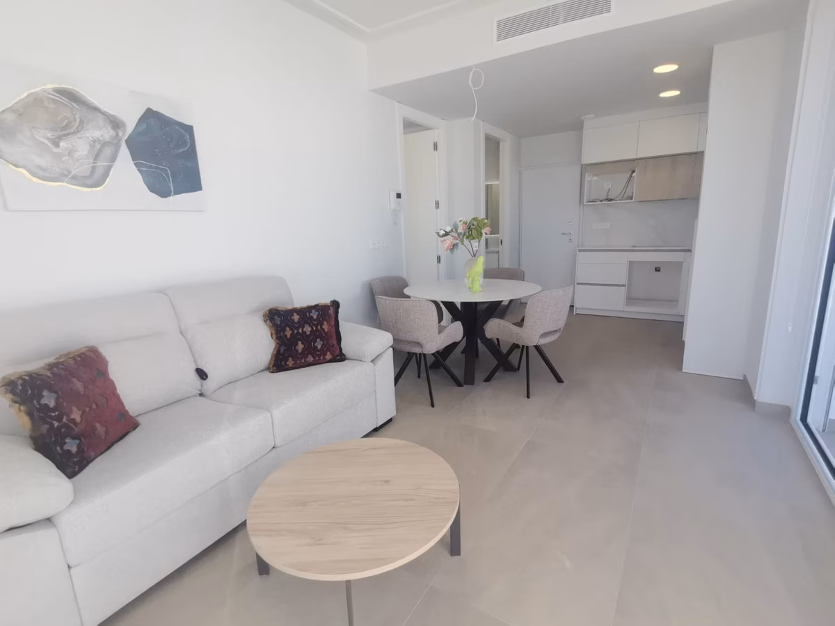 Wohnzimmer mit weißem Sofa, rundem Couchtisch und Essplatz an der offenen Küche