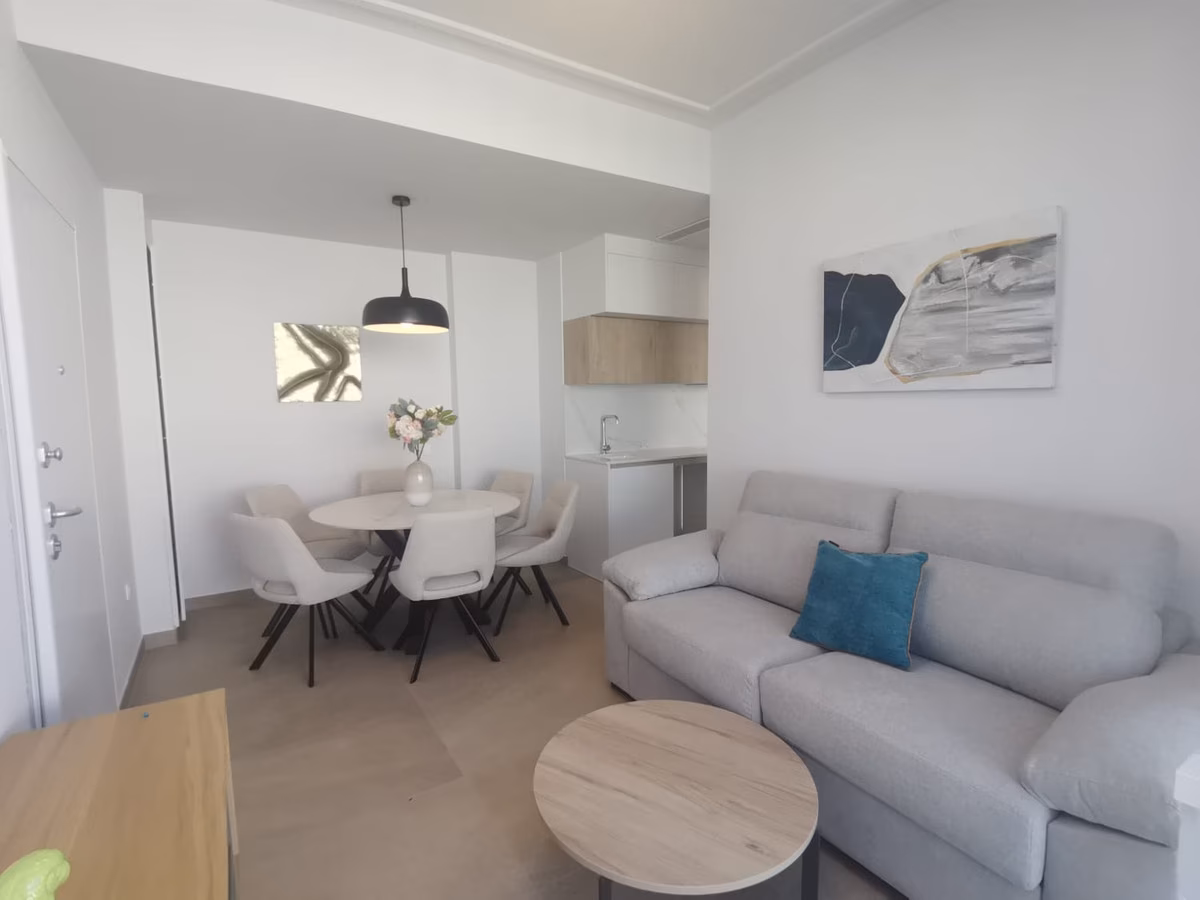 Zweites Wohnzimmer mit grauem Sofa, rundem Esstisch und Pendelleuchte