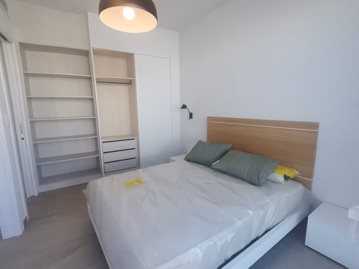 Schlafzimmer mit Doppelbett, Holzkopfteil und eingebauten Regalen