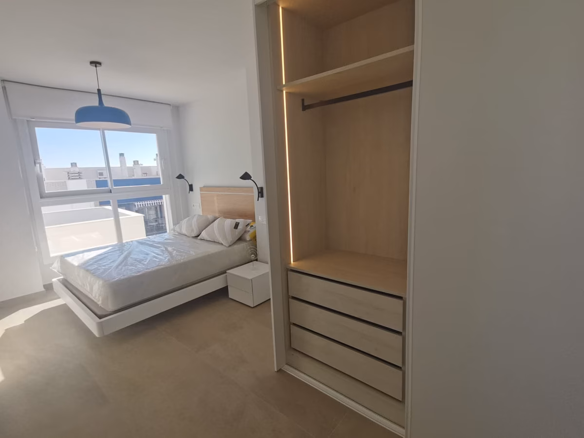 Schlafzimmer mit LED-beleuchtetem Einbauschrank und Fenster zur Terrasse