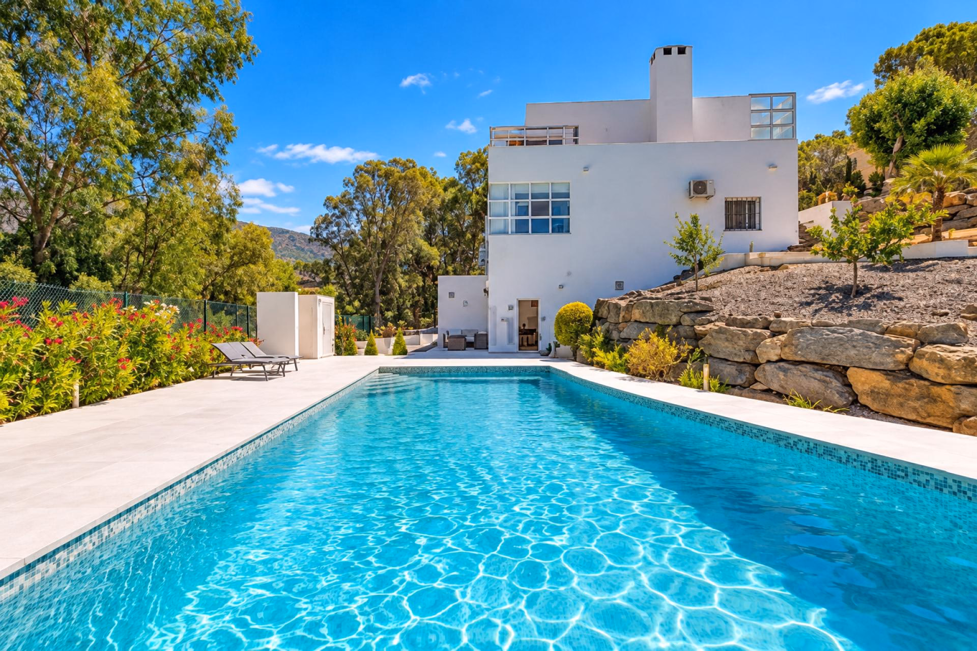 Saltwater pool with a stone-paved deck in front of the three-level villa