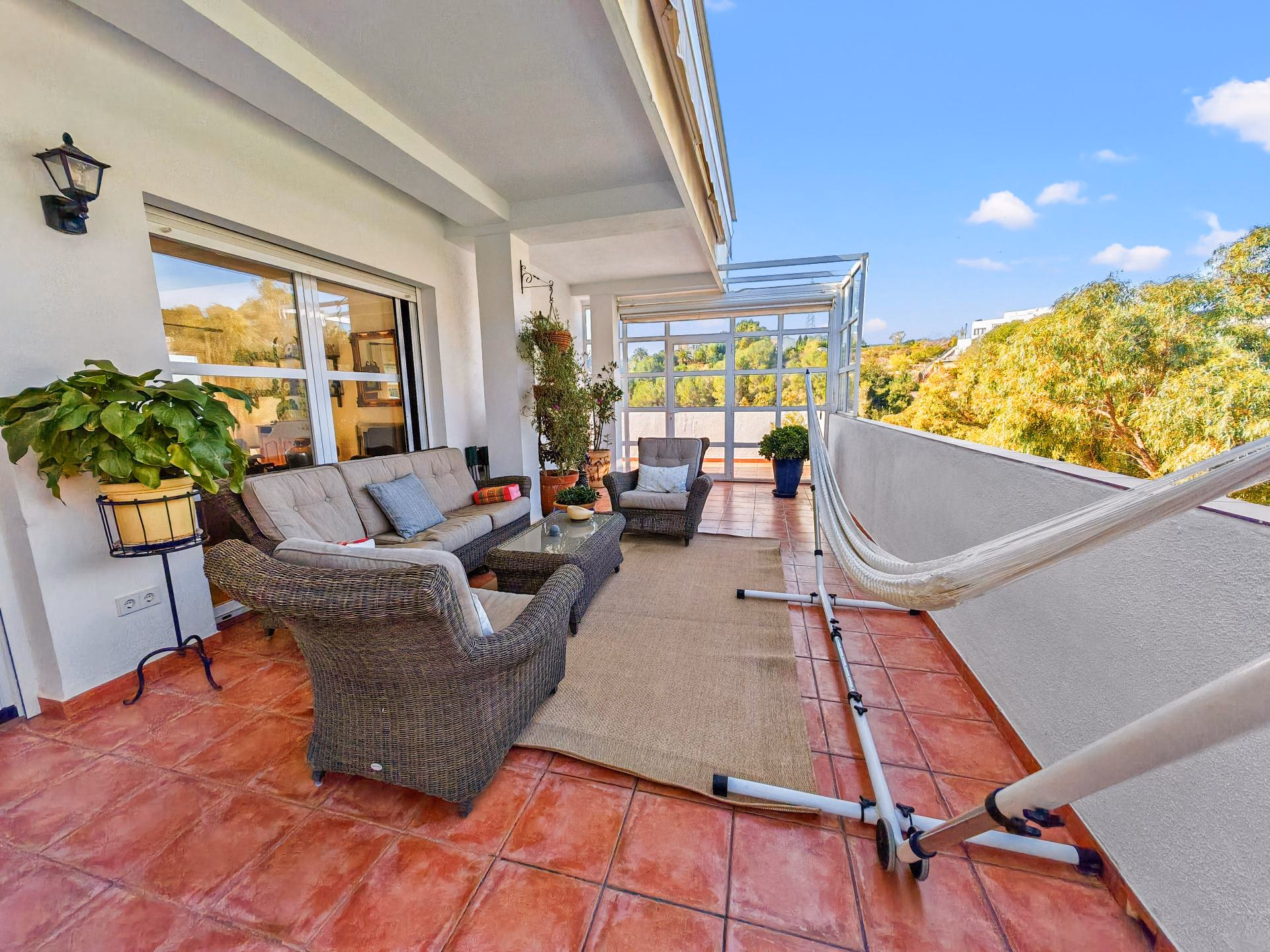 Terrace with garden furniture and a glass balustrade overlooking the trees