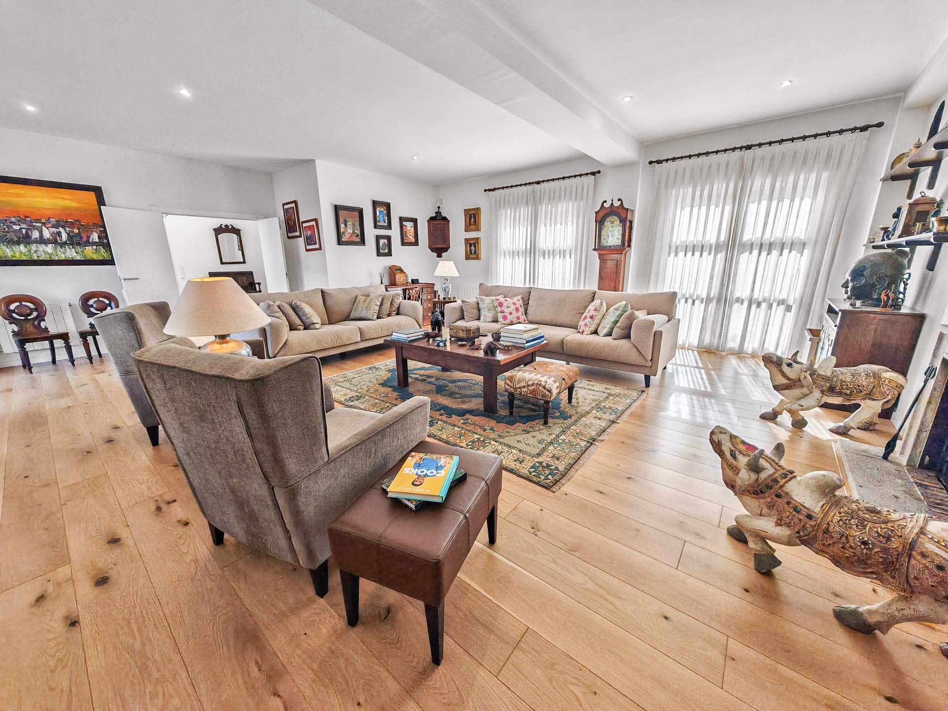Open-plan living room with sofas, rugs and windows onto the terrace