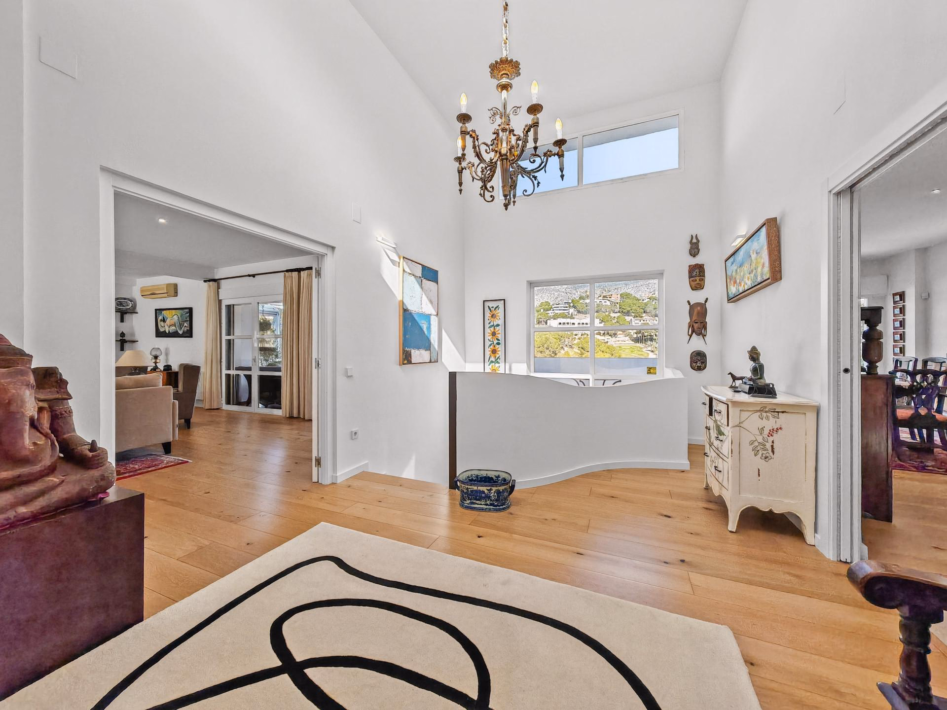 Hallway with high ceiling, chandelier and oak floor