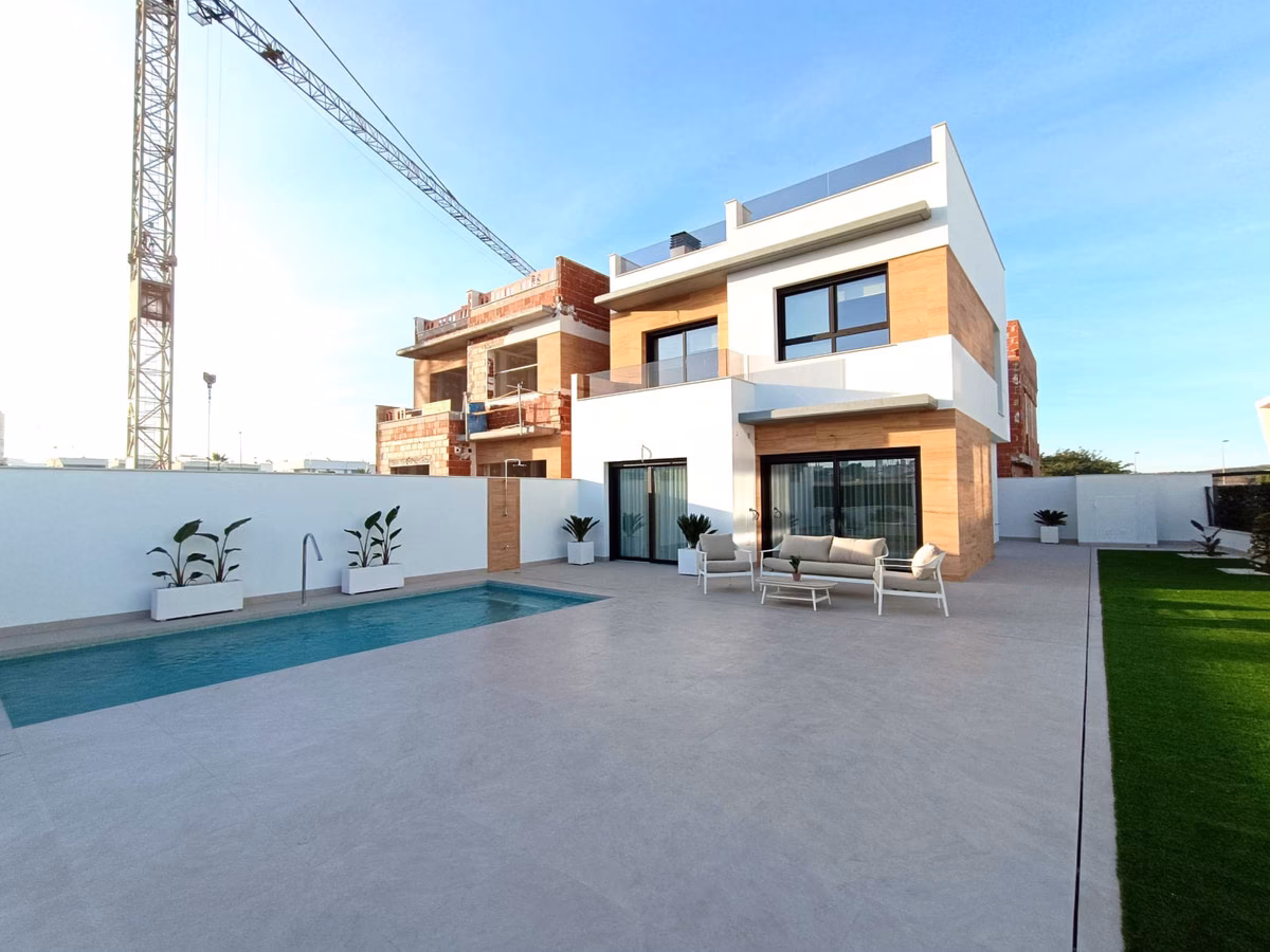 Parcela solada con la piscina y una franja de césped artificial detrás de la casa