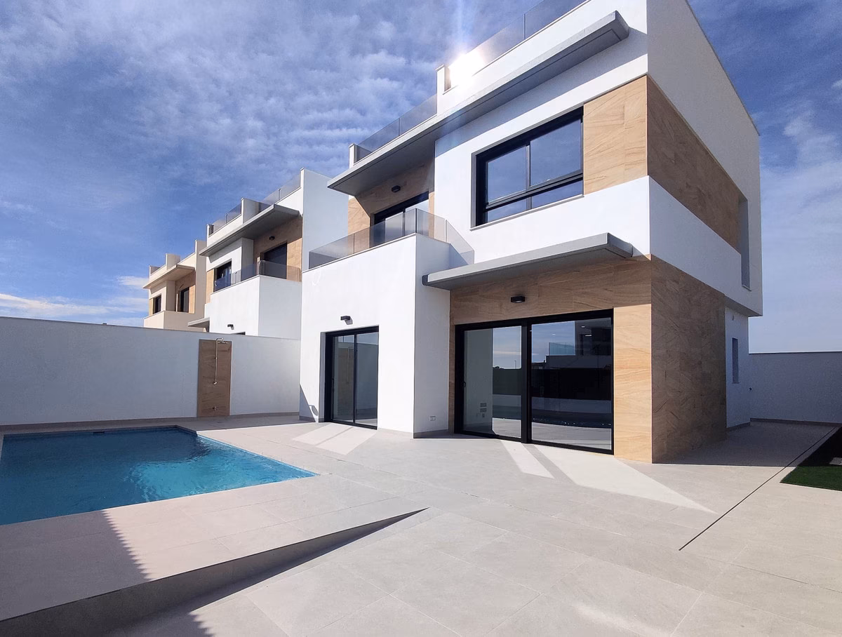 Fachada blanca con carpintería negra y la piscina delante