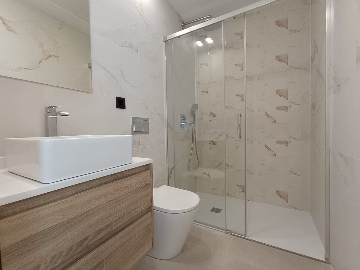 Baño alicatado en blanco efecto mármol con ducha a ras de suelo