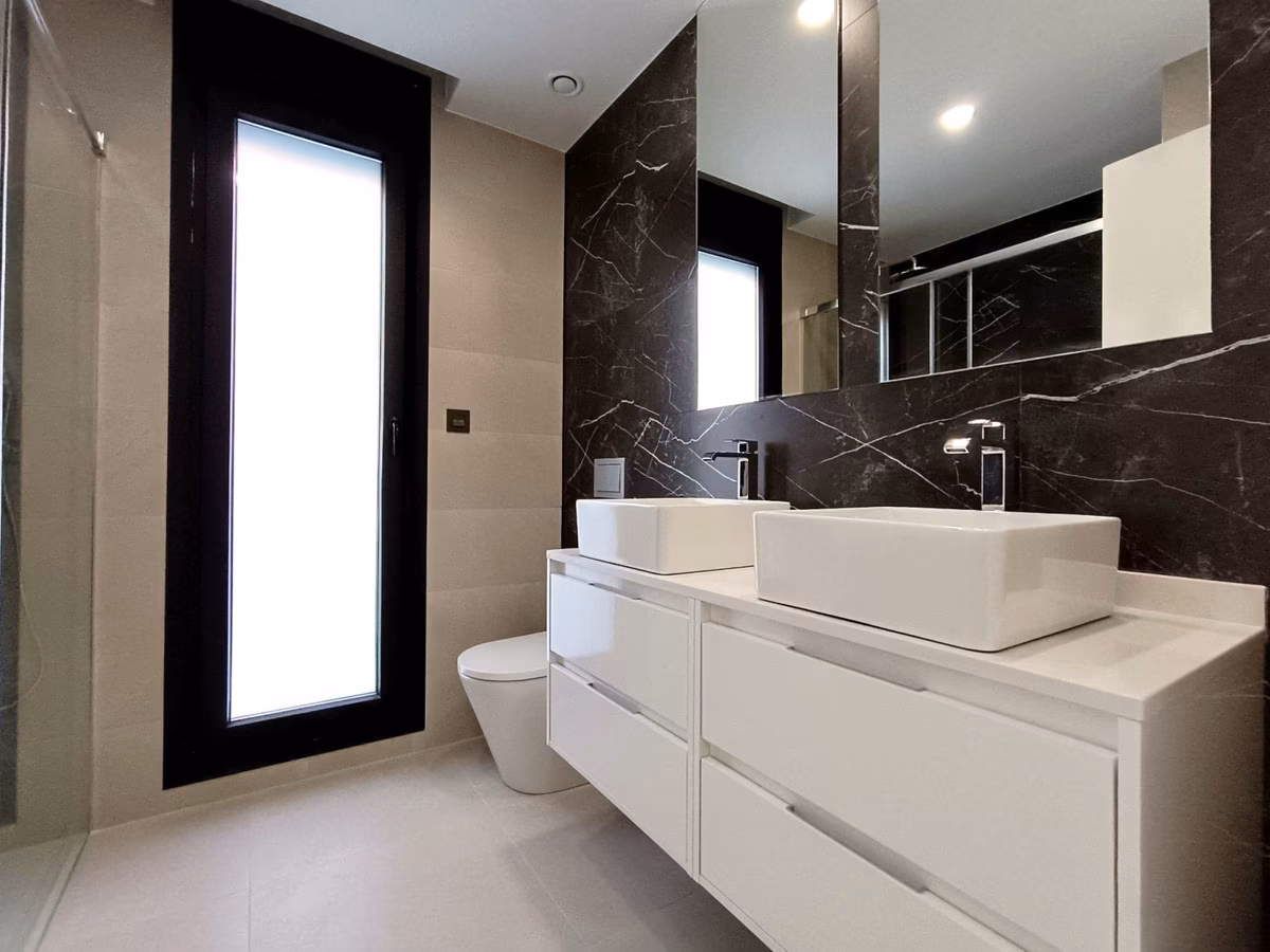 Baño con pared oscura efecto piedra y lavabo doble