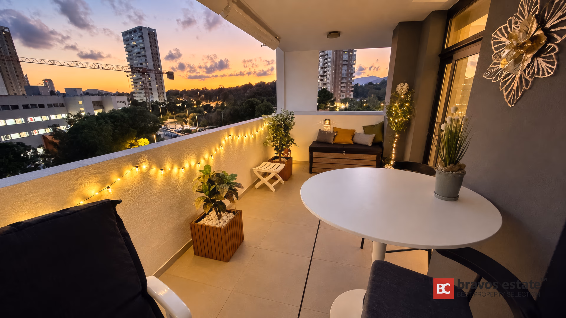 Terrasse au coucher du soleil avec table ronde, guirlande lumineuse et les tours de Benidorm