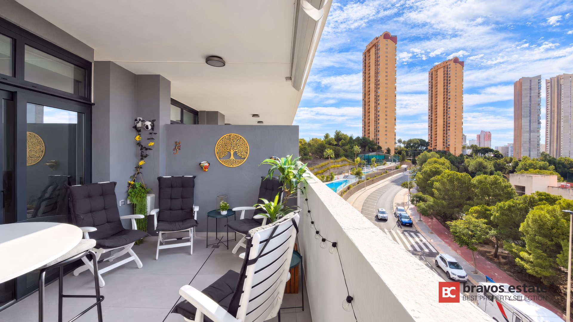 Terrasse avec chaises longues donnant sur la route, les pins et la skyline de Benidorm