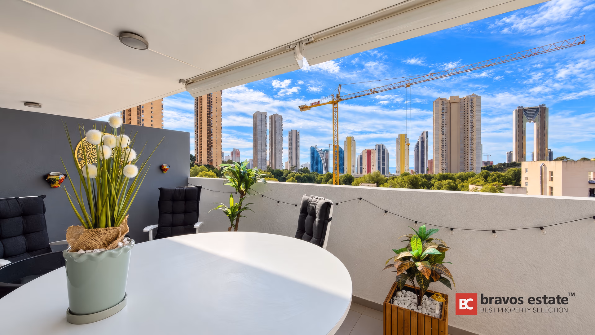 Coin salon de la terrasse avec coussins, plantes et vue sur la skyline de Benidorm
