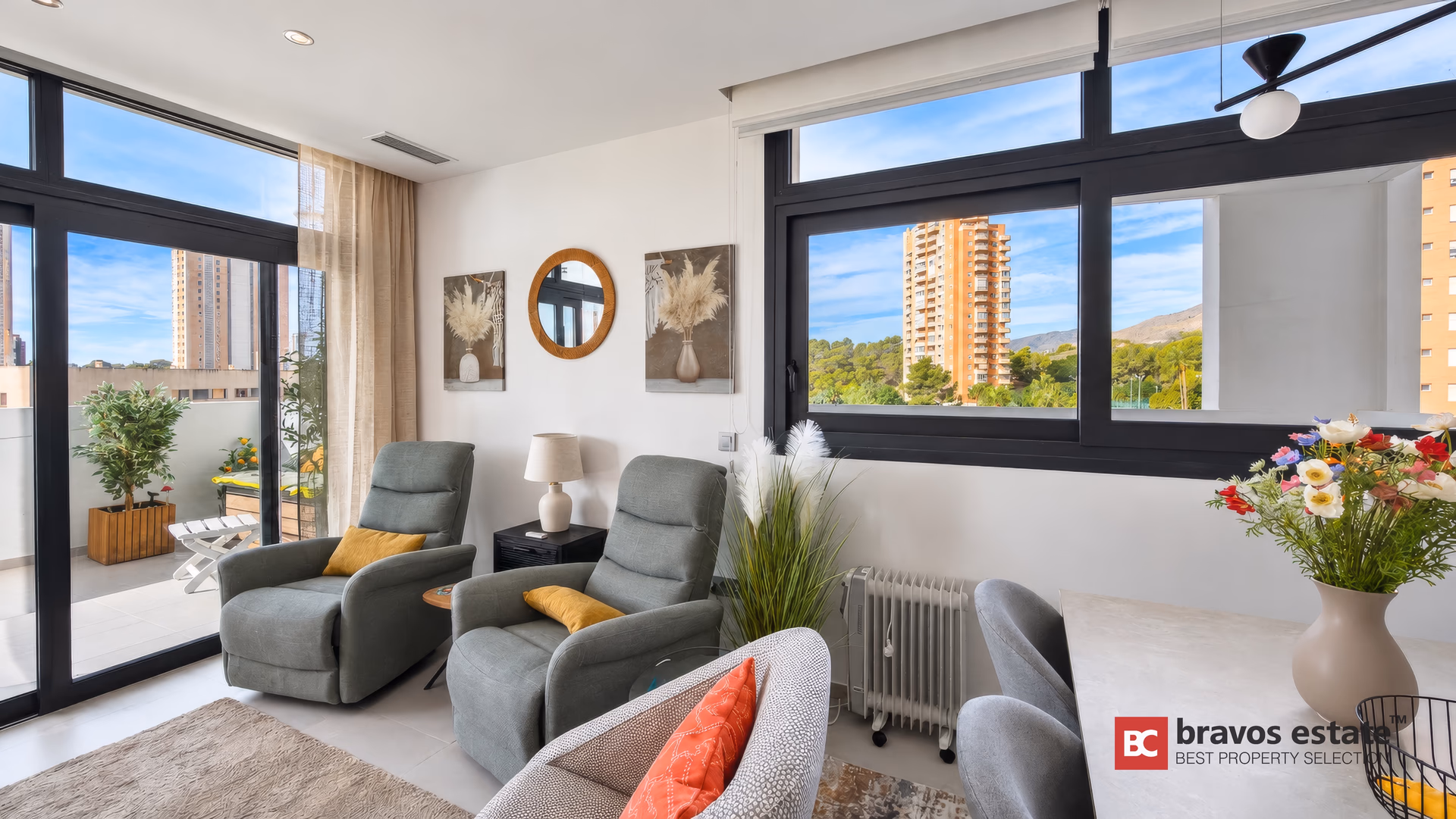 Salon avec deux fauteuils relax, miroir rond et la terrasse en arrière-plan