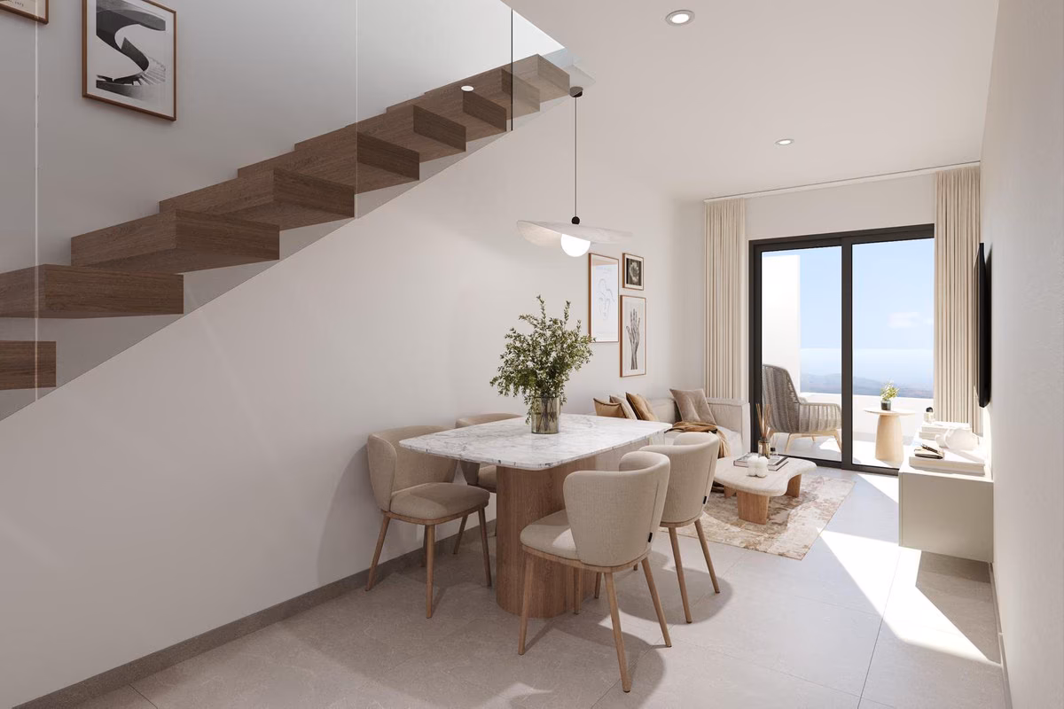 Comedor bajo una escalera abierta de madera, con la terraza al fondo