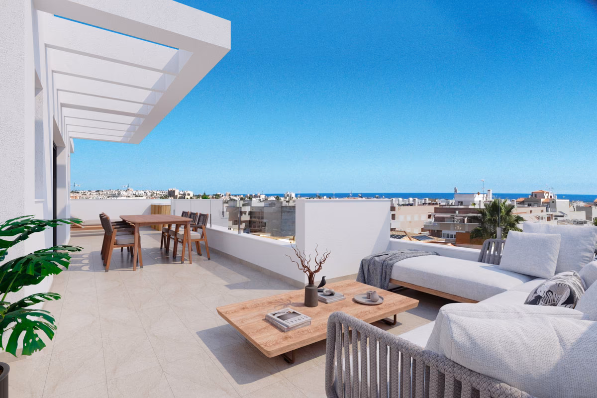 Terrasse en toit avec canapé et table à manger face à la ville et à la mer à Edificio Marcelina